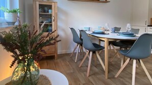 A dining area with a round table, six chairs, a cabinet with glass doors, and a hanging lamp.