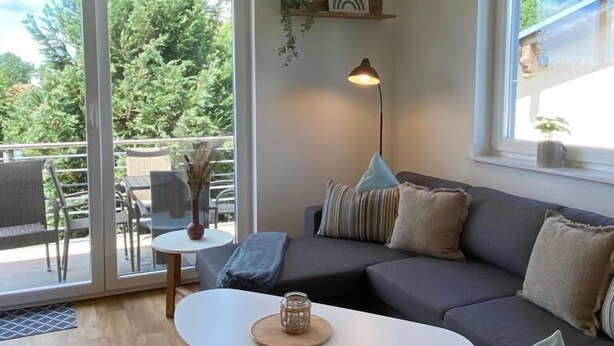 A modern living room with a grey sofa, a round coffee table, and a hanging lamp.