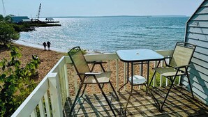 Una terraza de madera con una mesa y sillas con vista a la playa.