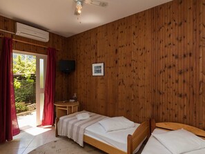 A wooden-paneled room with two beds, a TV, and a door leading to a garden. - Begovic Guest House - Standard Twin Room (Dubrovnik)