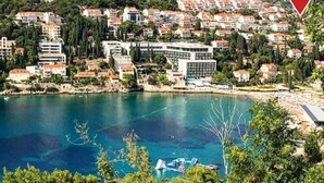 Un pueblo costero con edificios a lo largo del frente marítimo, un mar azul cristalino y montañas al fondo.