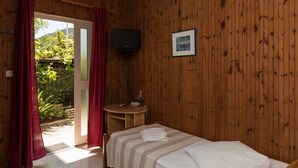 Una habitación con paneles de madera, una cama, un televisor y una pequeña mesa.