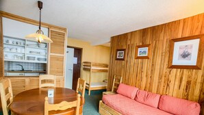 A compact room with a bunk bed, a dining table with chairs, a kitchen area, and a sofa. - Comfortable apartment near slopes and shops with balcony, pets allowed (Tignes)