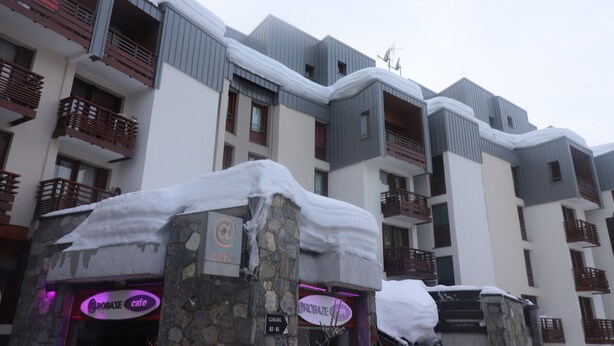 A multi-story hotel with balconies covered in snow, stone pillars, and neon cafe signs. - Comfortable apartment near slopes and shops with balcony, pets allowed (Tignes)