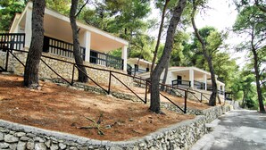 A row of white buildings with balconies, surrounded by trees and a stone wall. - Gattarella Family Resort - Self-catering accommodations in the pinewood  (Vieste)
