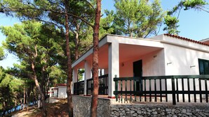 A white building with a stone wall and a wooden fence, surrounded by trees. - Gattarella Family Resort - Self-catering accommodations in the pinewood  (Vieste)