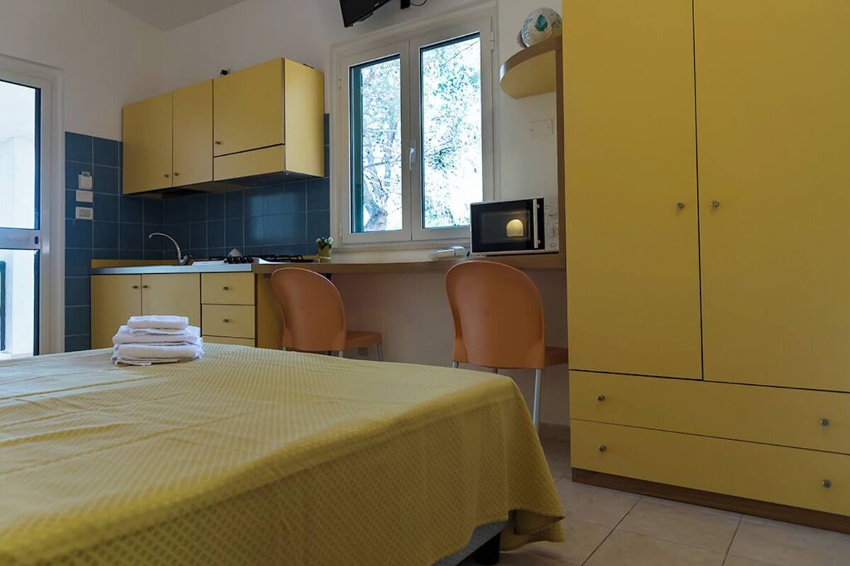 Una habitación compacta con cama, kitchenette pequeña y ventana.