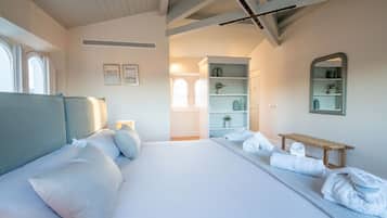 A spacious bedroom with a large bed, a wooden bench, and a mirror on the wall.