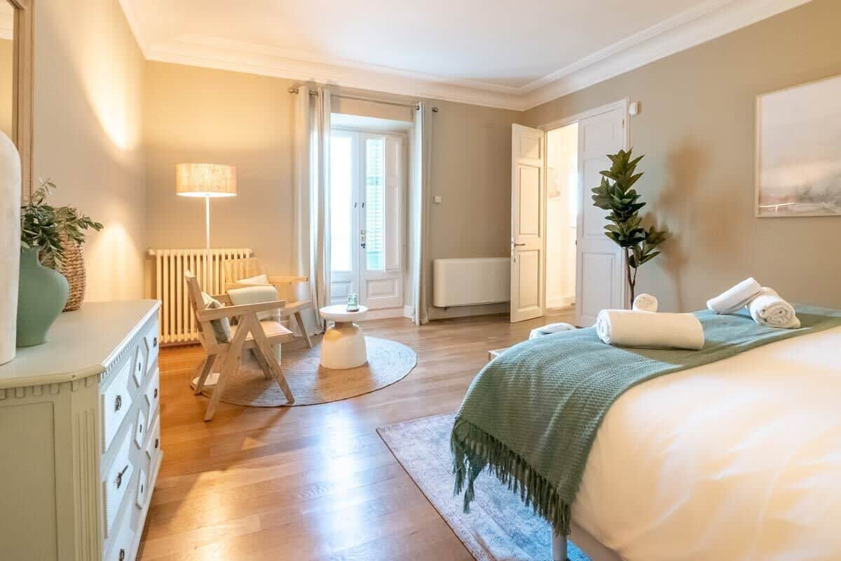 Ein Schlafzimmer mit Bett, Schreibtisch, Stuhl, Lampe und Heizkörper.
