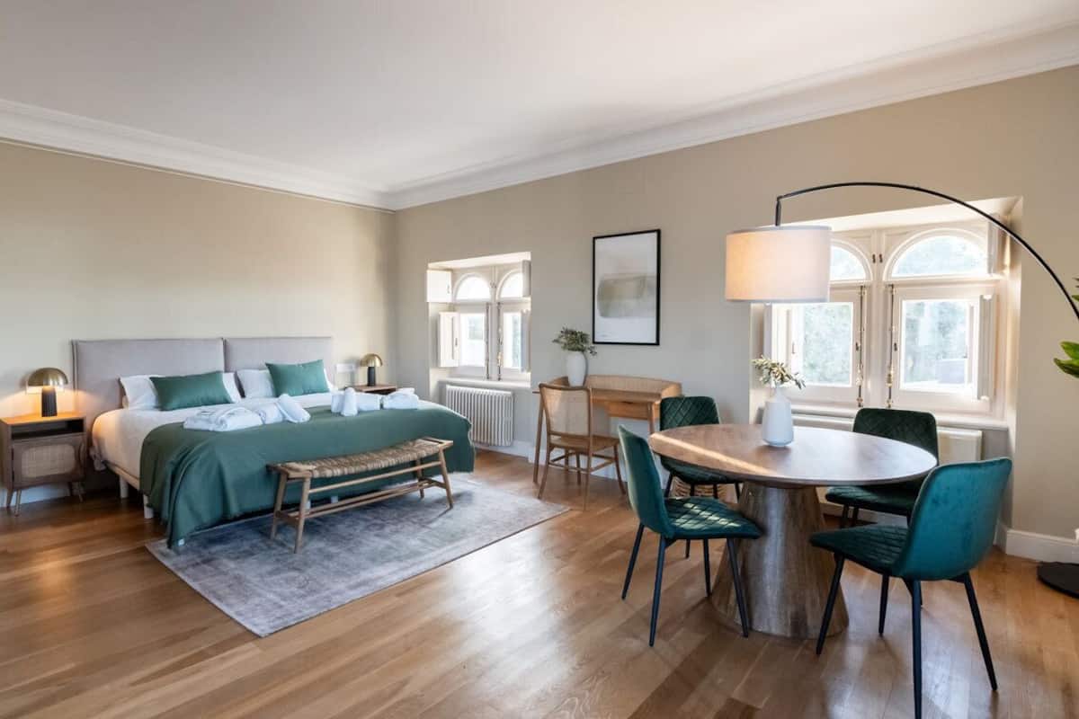 Ein Schlafzimmer mit einem Bett, Nachttischen, einem Schreibtisch und Stühlen.
