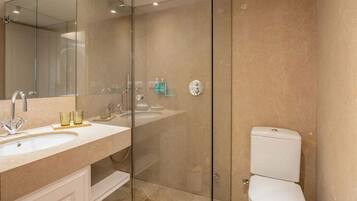 A modern bathroom with a glass-enclosed shower, a white sink, and a toilet.