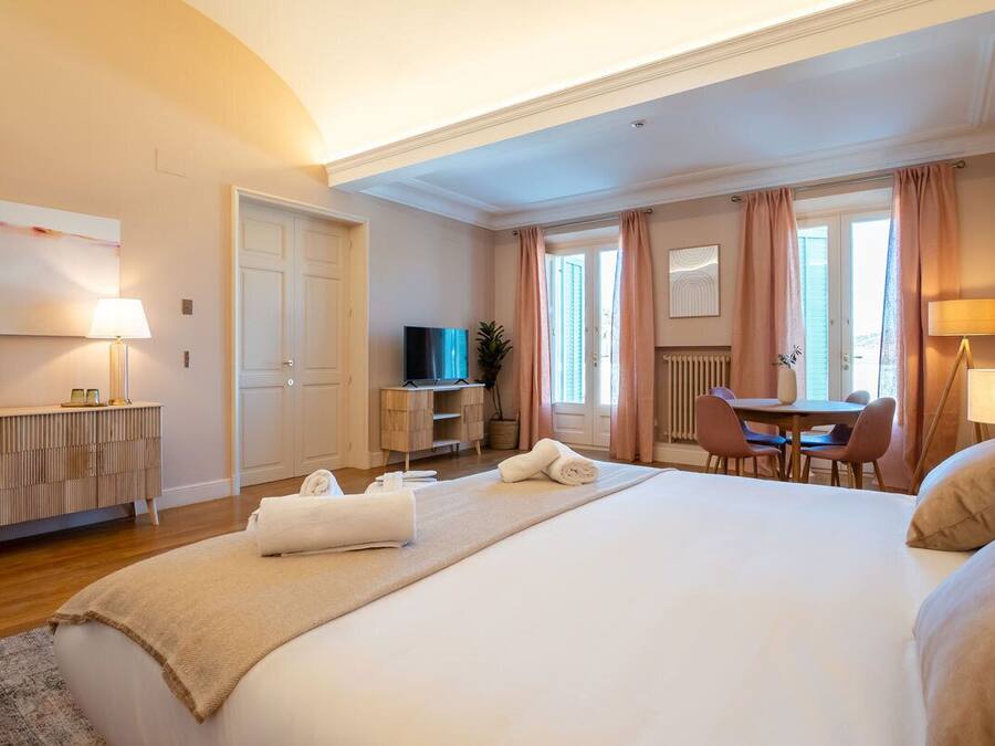 Een hotelkamer met een groot bed, een bureau, een stoel, een televisie en een raam met gordijnen.