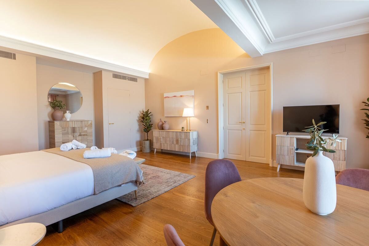 Una habitación de hotel con cama, escritorio, televisión y mesa de comedor.