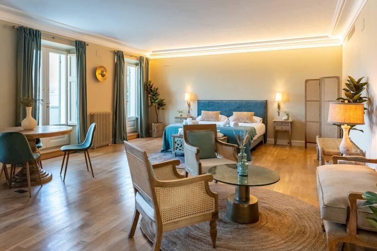 Ein Hotelzimmer mit einem Bett, zwei Stühlen, einem runden Tisch, einer Lampe und einer Pflanze.