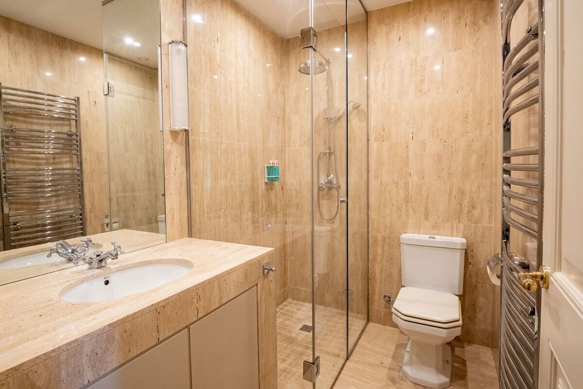 A modern bathroom with a glass-enclosed shower, a sink with a mirror, and a toilet.