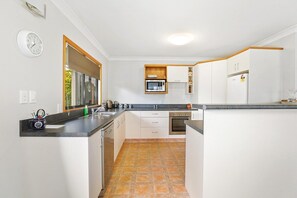 A compact kitchen with white cabinets, a microwave, and a stove.