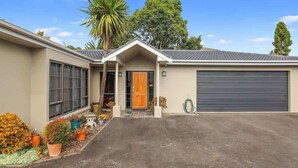 Une maison de plain-pied avec un garage à l’avant, une porte d’entrée en bois et une allée.
