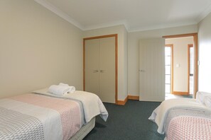 Ein Hotelzimmer mit zwei Einzelbetten, einer Tür und einem Fenster.