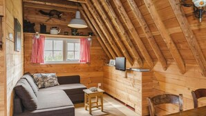 A cozy cabin interior with a wooden ceiling, a sofa, a small table, and a television. - Holiday Home in Ruinerwold With Garden (Ruinerwold)