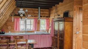 A cozy kitchen with wooden walls, a checkered tablecloth-covered table, and a wooden cabinet. - Holiday Home in Ruinerwold With Garden (Ruinerwold)