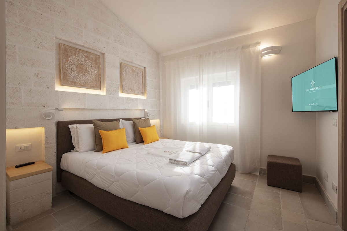 Une chambre moderne avec un grand lit, des tables de chevet, un téléviseur à écran plat et des œuvres d’art accrochées au mur.