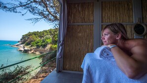 En person som kopplar av på en balkong med utsikt över havet och en klippig kustlinje.