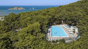 En pool omgiven av frodig grönska, med utsikt över havet och en liten ö i fjärran.