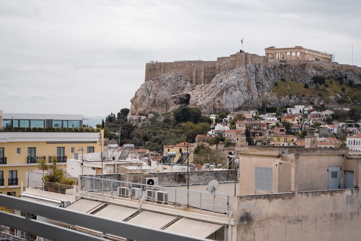 A rooftop terrace with a view of a historic building on a hill, surrounded by residential buildings.