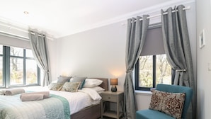 A bedroom with a bed, a chair, a nightstand, and a window with curtains. - Woodend Croft (Ellon)