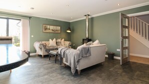 A living room with a fireplace, a dining table, and a staircase. - Woodend Croft (Ellon)