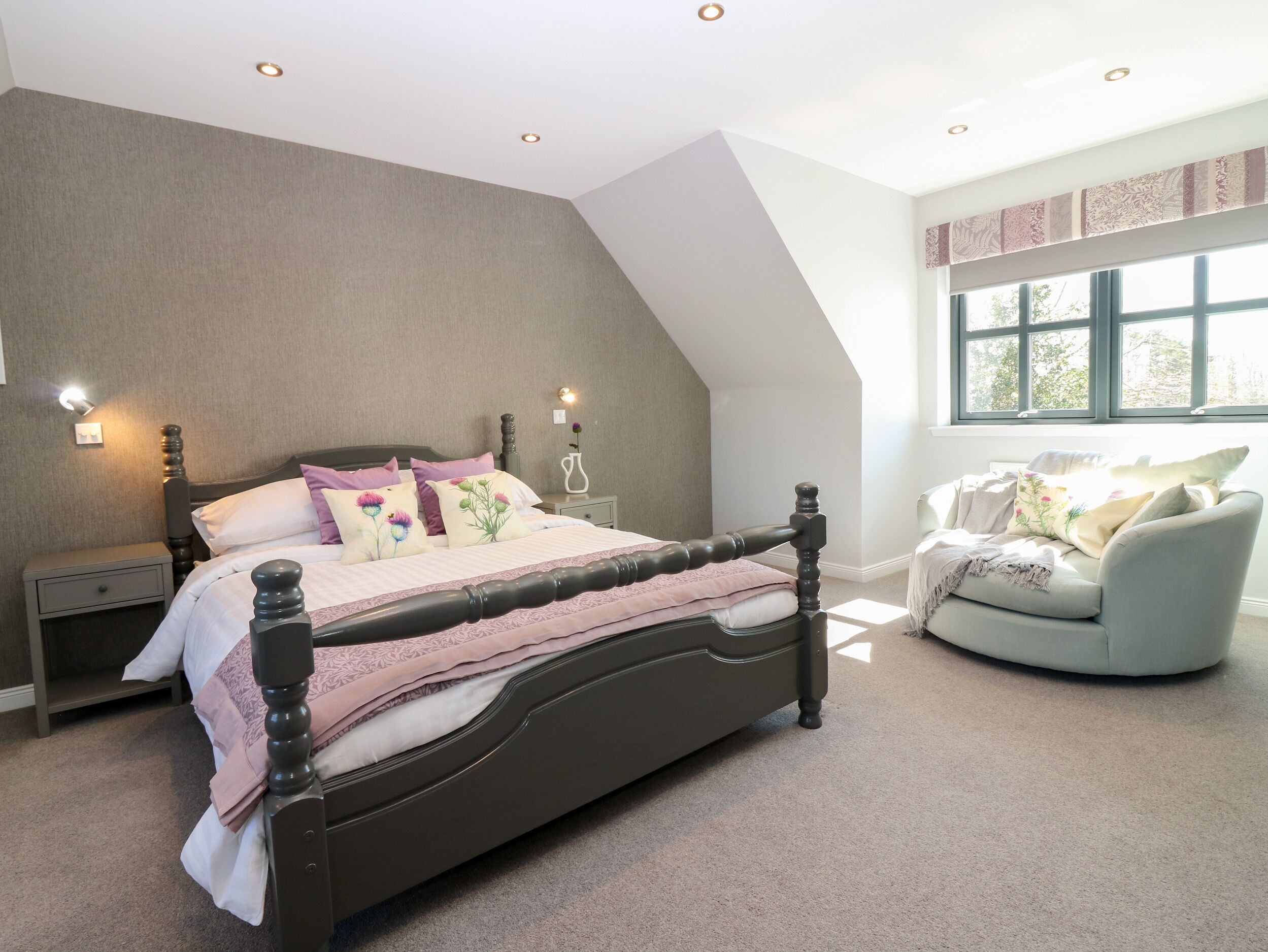 A bedroom with a bed, nightstands, a chair, and a window.