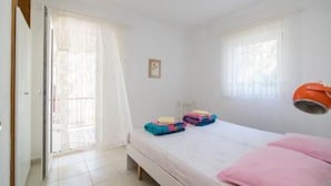 A bedroom with a bed, a window with curtains, a door, and a small framed picture on the wall. - Apartments Boguvila - Two-bedroom Family Apartment With Terrace - (Supetar)