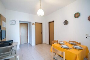 A dining area with a table set for four, a television, and a clock on the wall.