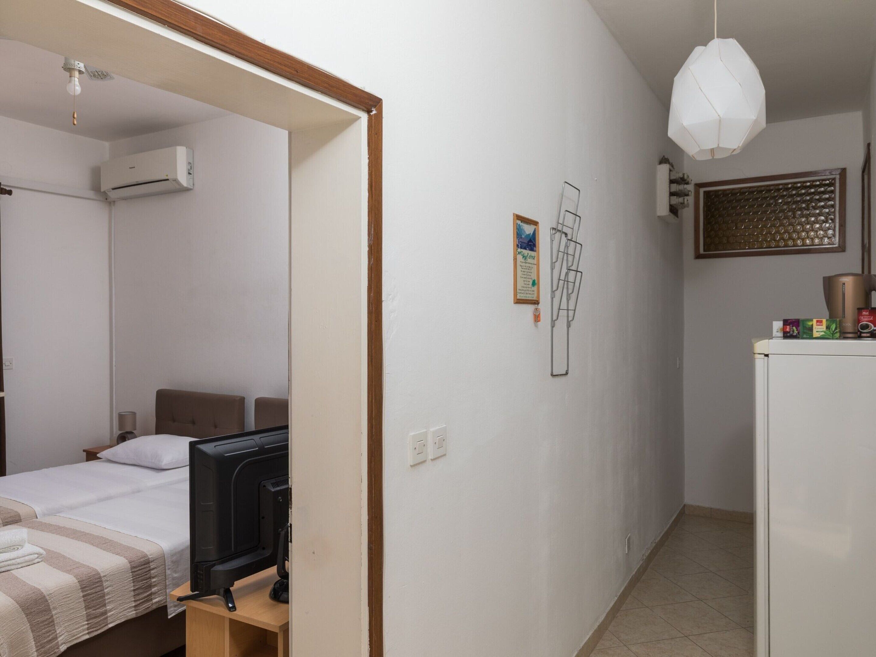 A bedroom with a bed, a TV, and an air conditioning unit.