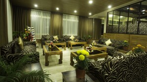 A modern living room with patterned sofas, wooden coffee tables, and potted plants. - New Orchid Lords Inn Gangtok  (Gangtok)