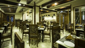 A restaurant with wooden furniture and a high ceiling with exposed beams. - New Orchid Lords Inn Gangtok  (Gangtok)