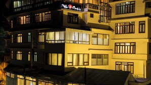 A multi-story hotel with illuminated windows and balconies. - New Orchid Lords Inn Gangtok  (Gangtok)