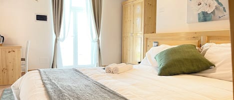 Ein Schlafzimmer mit einem Bett, einem Holzschrank, einem Bild an der Wand und einem Fenster mit Vorhängen.