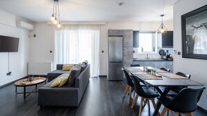 A modern living room with a sofa, coffee table, and dining area with chairs and a table. - Duplex Penthouse with Sauna & Acropolis View (Athens)