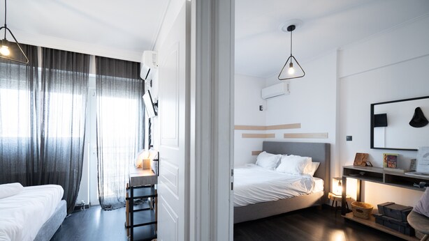 A modern hotel room with a bed, bedside table, and a desk with a chair. - Duplex Penthouse with Sauna & Acropolis View (Athens)
