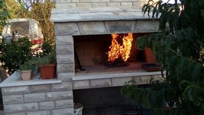 A stone-built outdoor fireplace with a visible fire. - Apartments Marita - Two Bedroom Apartment (Korčula)