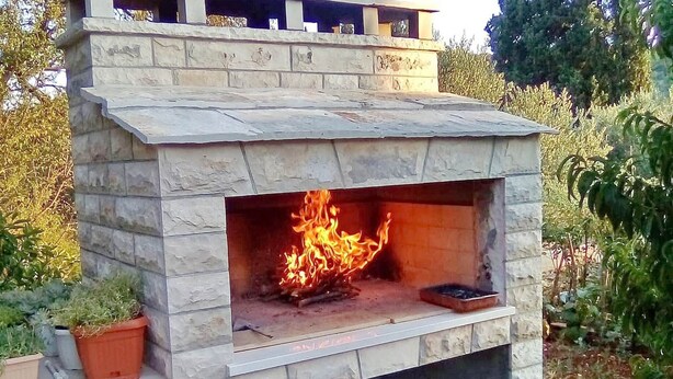 A stone-built outdoor fireplace with a fire burning inside. - Apartments Marita - Two Bedroom Apartment (Korčula)