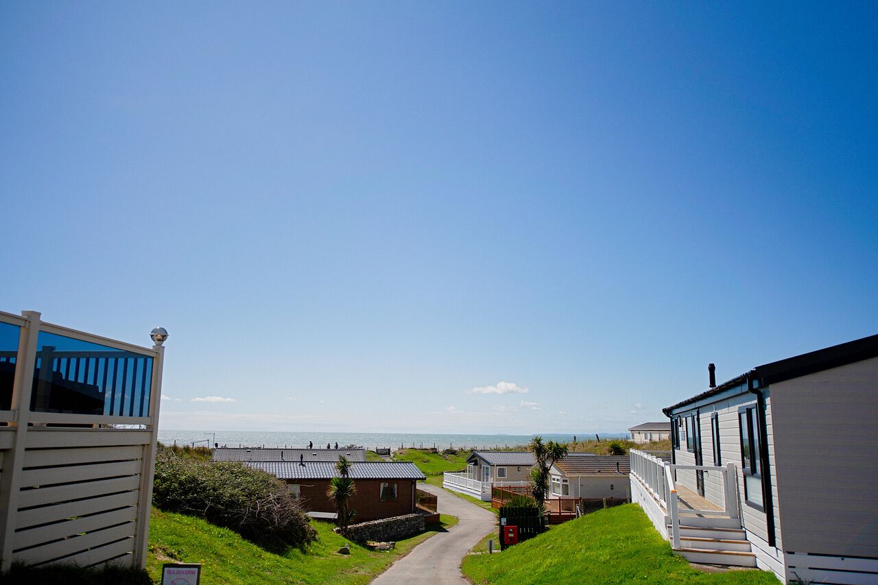 Une rangée de maisons mobiles, avec un chemin qui mène à la plage.
