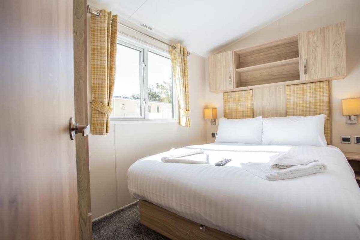 Une chambre d’hôtel avec un lit, une tête de lit en bois, des lampes de chevet et une fenêtre avec des rideaux.