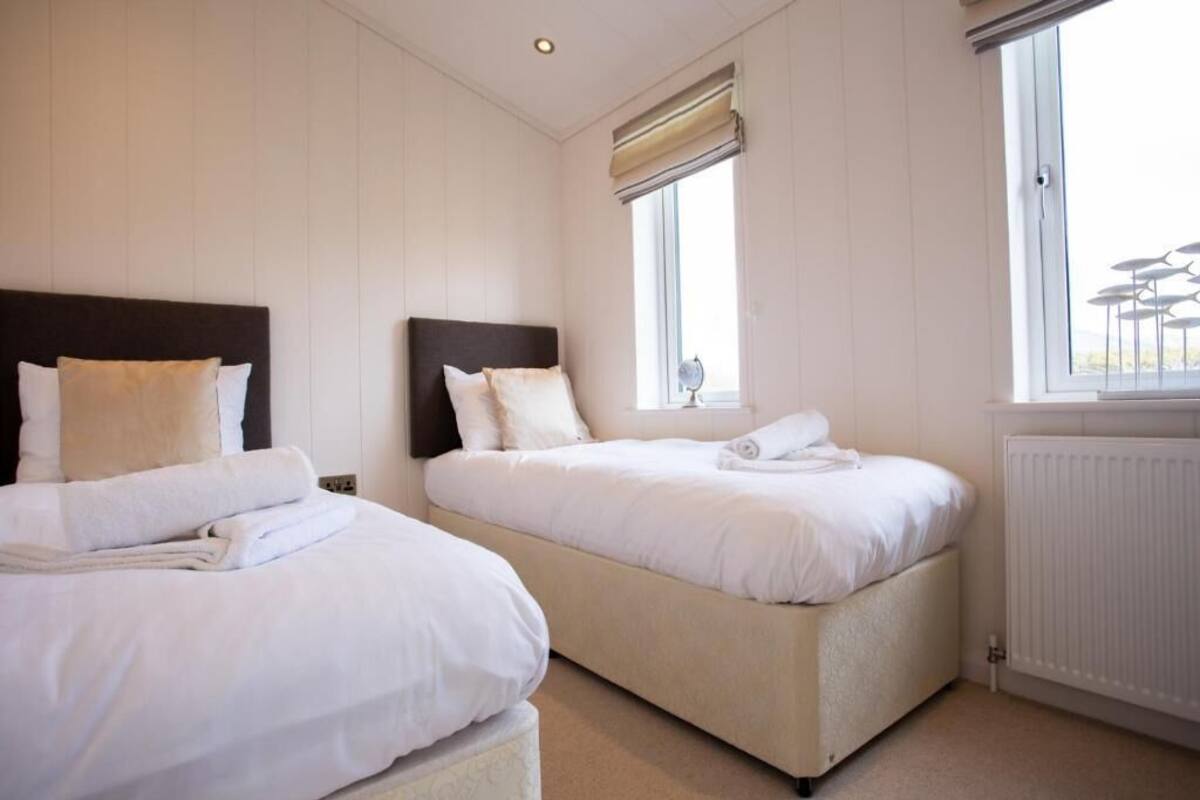 Une chambre d’hôtel avec deux lits, une fenêtre avec des stores, un radiateur et une vue sur l’extérieur.