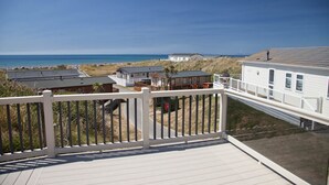 A coastal residential area with houses, a beach, and a clear sky. - Barmouth Bay Holiday Park (Talybont)