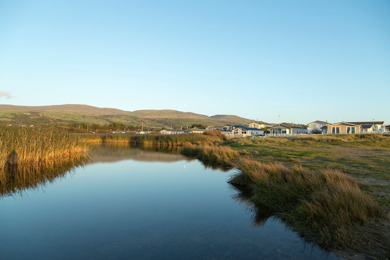 A tranquil lakeside setting with houses and a clear sky.