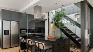 Eine moderne Küche mit einer zentralen Kochinsel, Barhocker und einer Treppe, die in einen oberen Bereich führt.