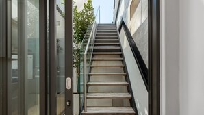 Eine moderne Treppe mit Glasgeländern und einem Steingrund, die zu einer oberen Etage führt.