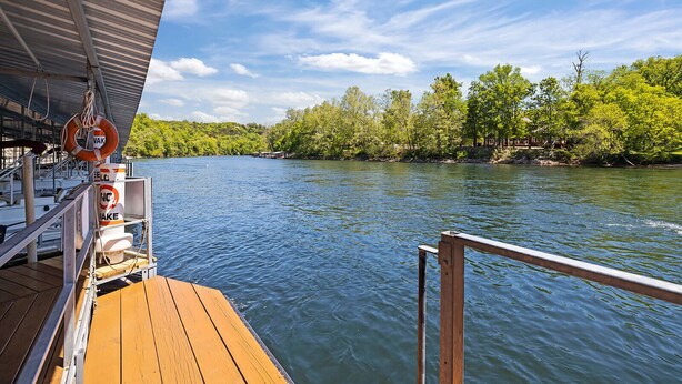 A wooden deck with a railing, a lifebuoy, and a sign indicating no swimming.